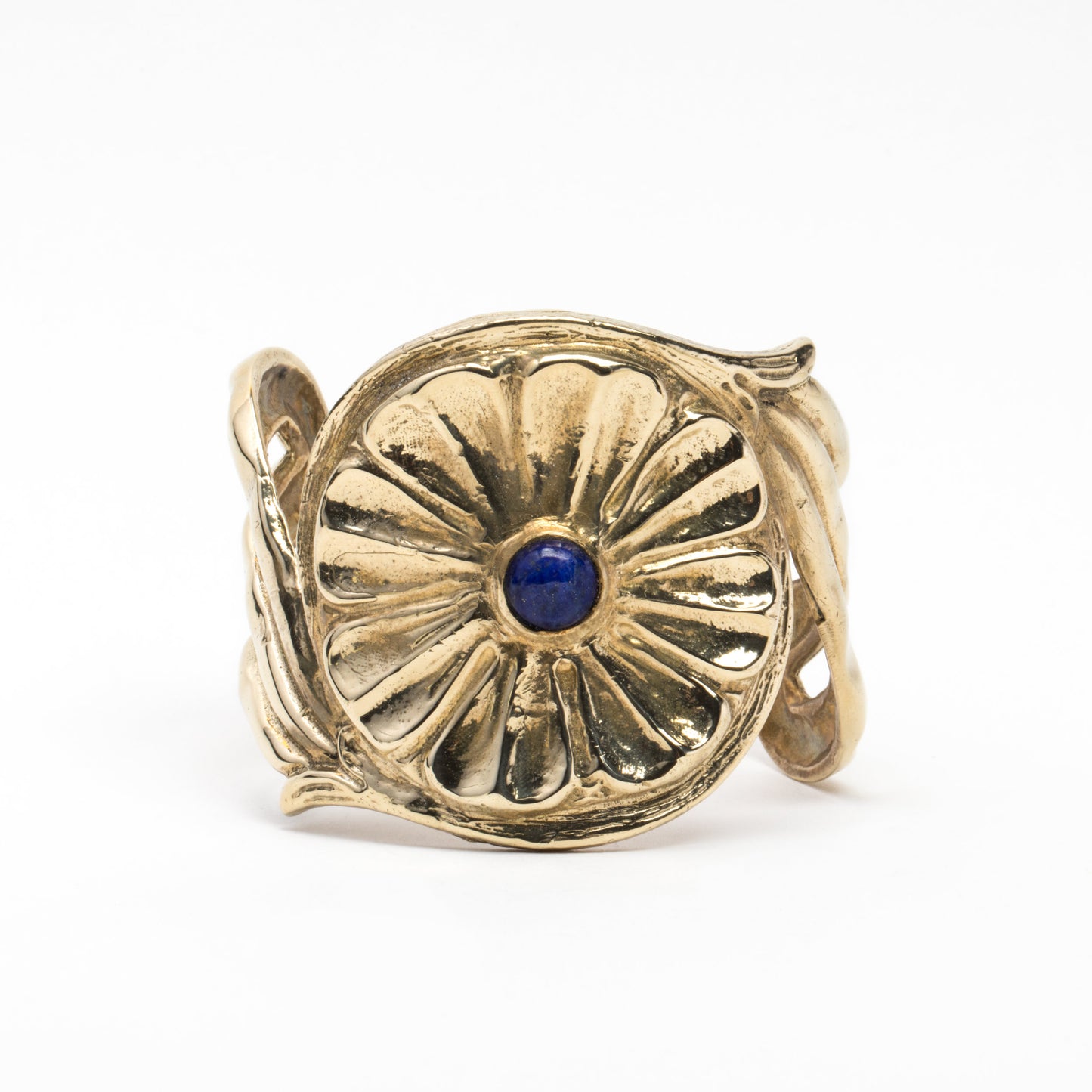 A gold-colored metal cuff bracelet with a central blue stone and decorative patterns around the edge.